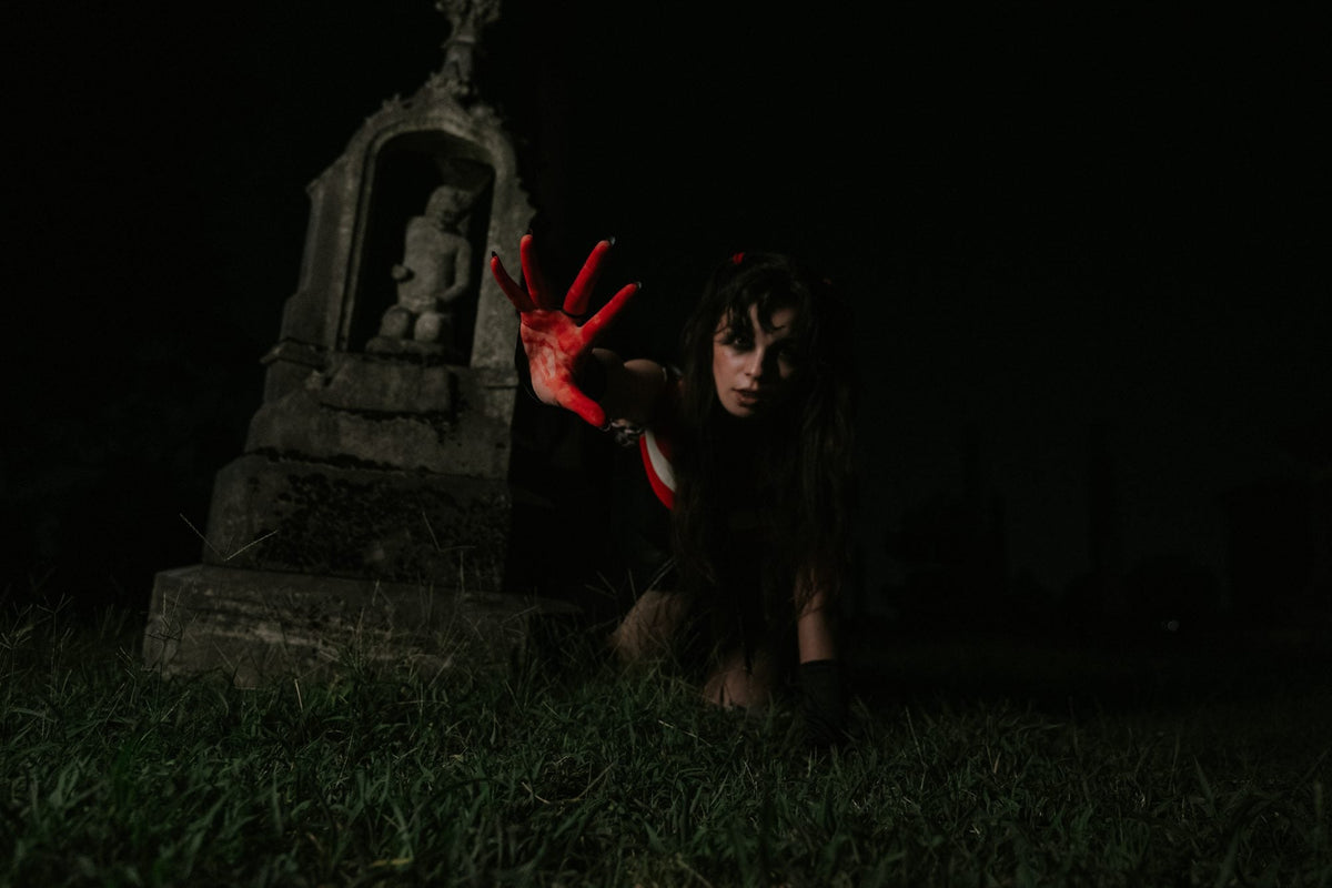 Mary Jo reaching toward the camera with a bloody hand in a graveyard